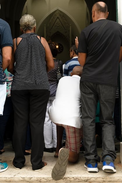 A diverse group of community members, including individuals from different ethnic and religious backgrounds, receiving aid supplies from a US citizen aid worker. The scene should depict fairness and equal treatment.