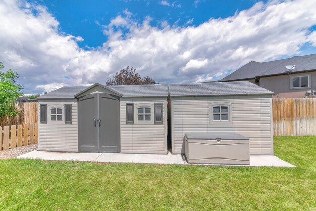 A house with reinforced windows and a secure roof, surrounded by a well-maintained yard. The landscape includes flood barriers strategically placed to protect the foundation. The overall image conveys a sense of structural integrity and preparedness against natural disasters.