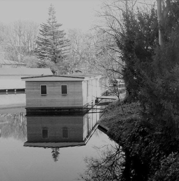 A split-screen image showing a vulnerable house on one side (e.g., near a river, old construction) and a well-prepared house on the other side (e.g., reinforced foundation, cleared surroundings, emergency kit visible).