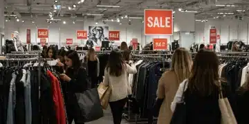 Mujer joven sonriendo mientras compra ropa de marca en una tienda durante el Black Friday.