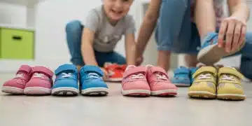 Calzado infantil 2025: Talla correcta y prevención de problemas Variedad de calzado infantil de diferentes colores y tallas, con un niño probándose un zapato.